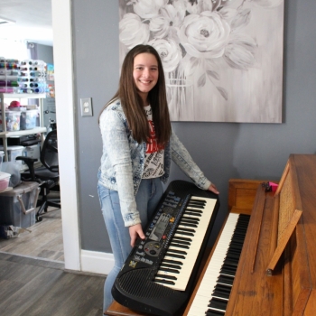 Arelis comparing her old keyboard to the new piano