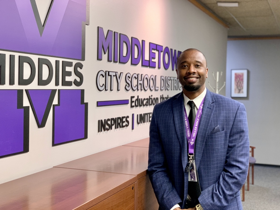 Mr. Kee Edwards standing in front of MCSD logo sign